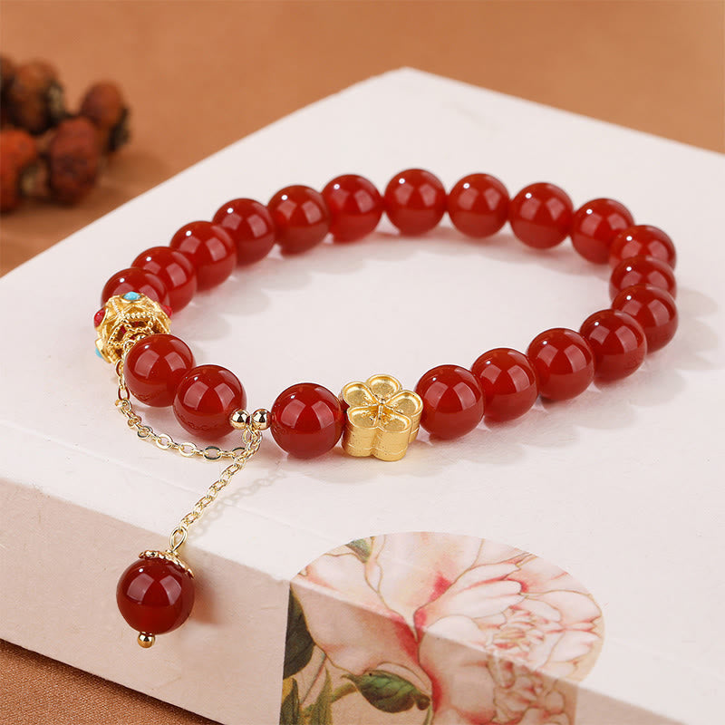 Armband Roter Achat mit goldenem Blütenanhänger elegant präsentiert