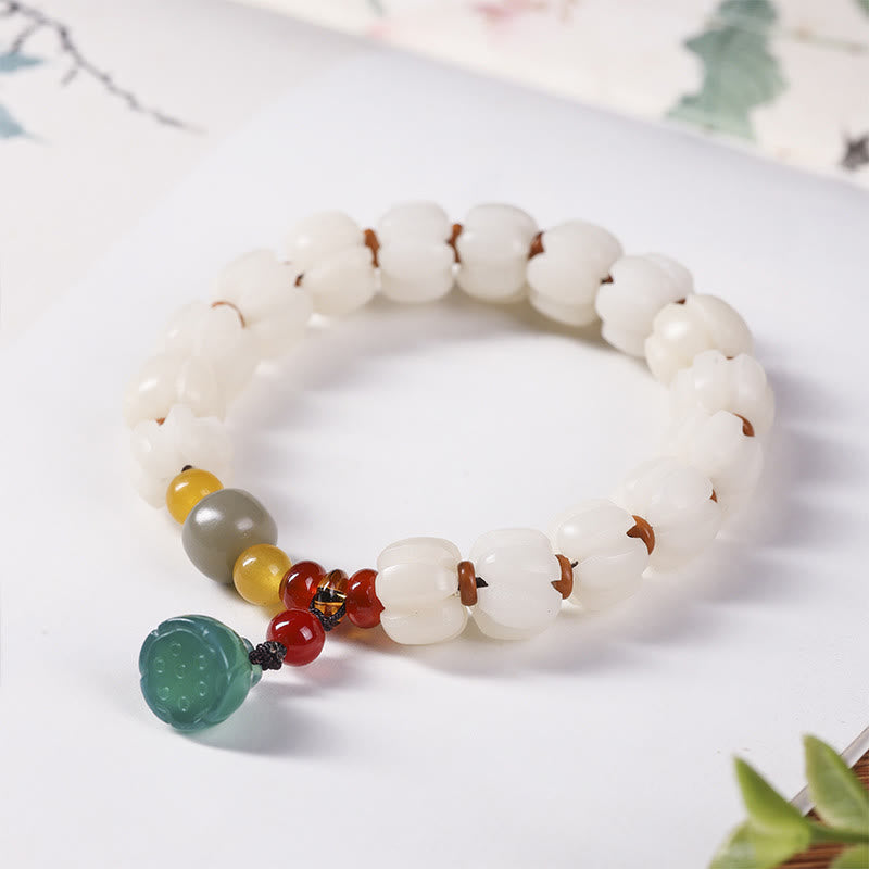 Weißes Bodhi-Armband mit grünem Lotus-Anhänger elegant präsentiert.