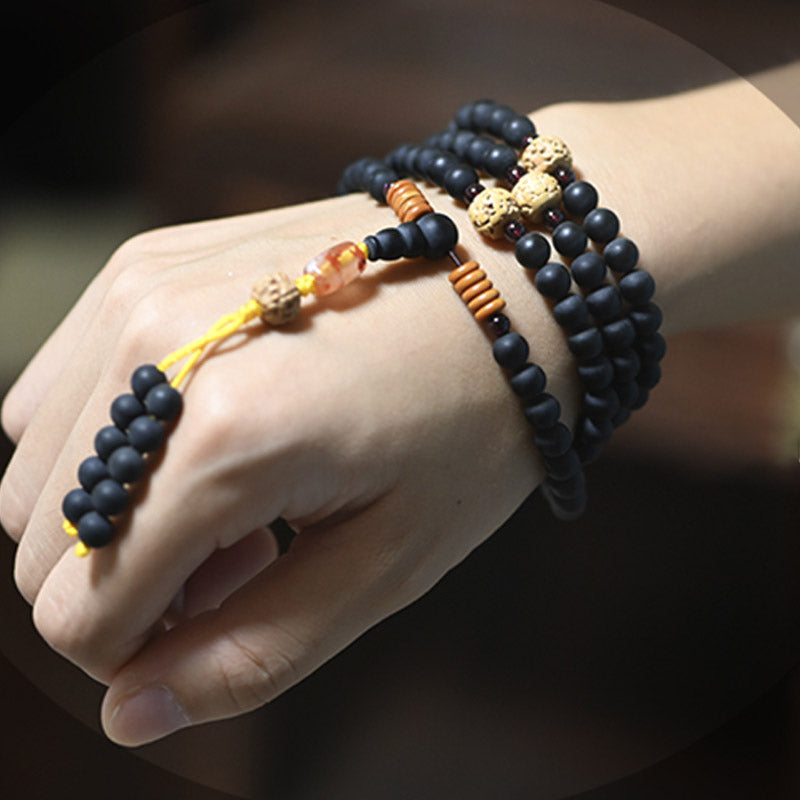 Mala Armband am Handgelenk schwarze Perlen goldene Akzente Heilstein Schmuck