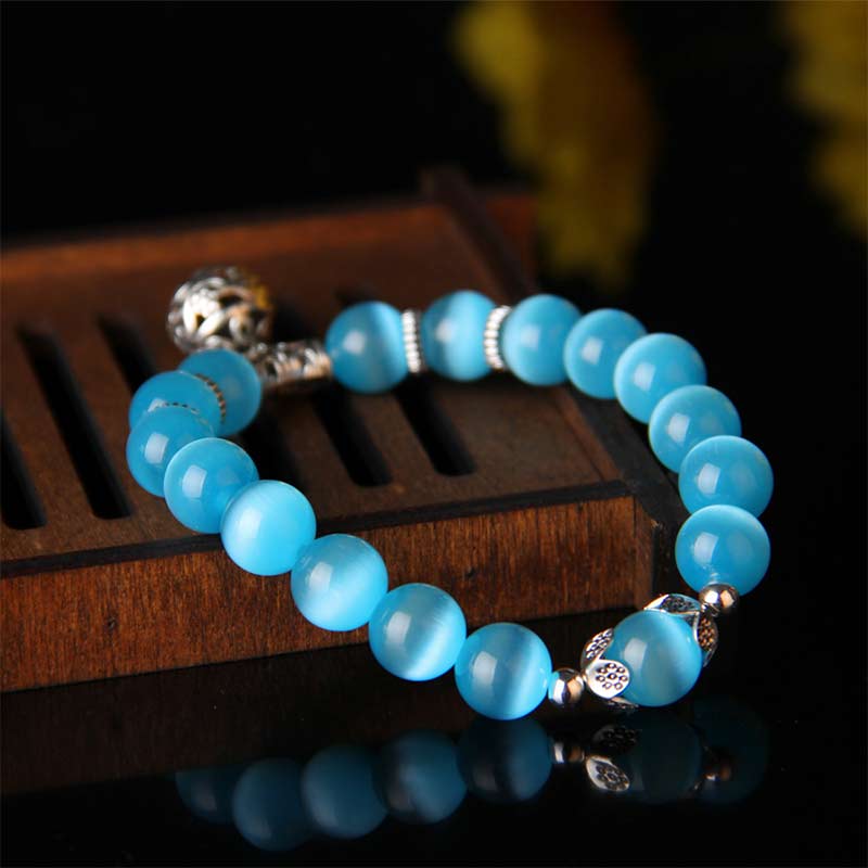 Blaues Catseye Armband mit silbernen Perlen elegant präsentiert.