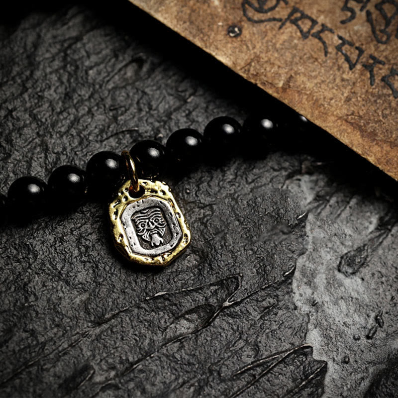 Mala Schwarzer Onyx mit goldenem Anhänger auf Steinhintergrund