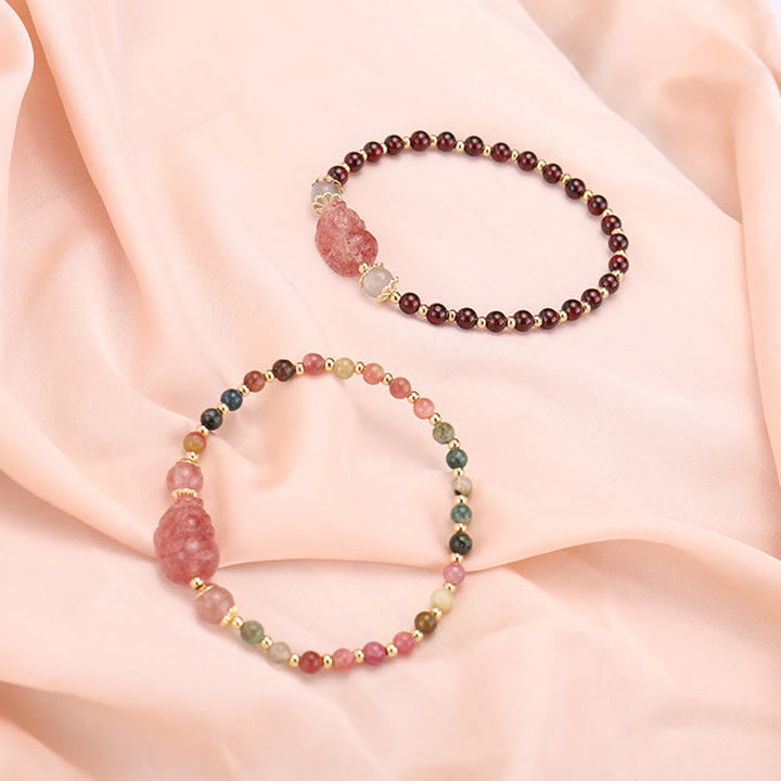 Zwei Armbänder mit Erdbeerquarz und Mondstein Perlen elegant präsentiert.