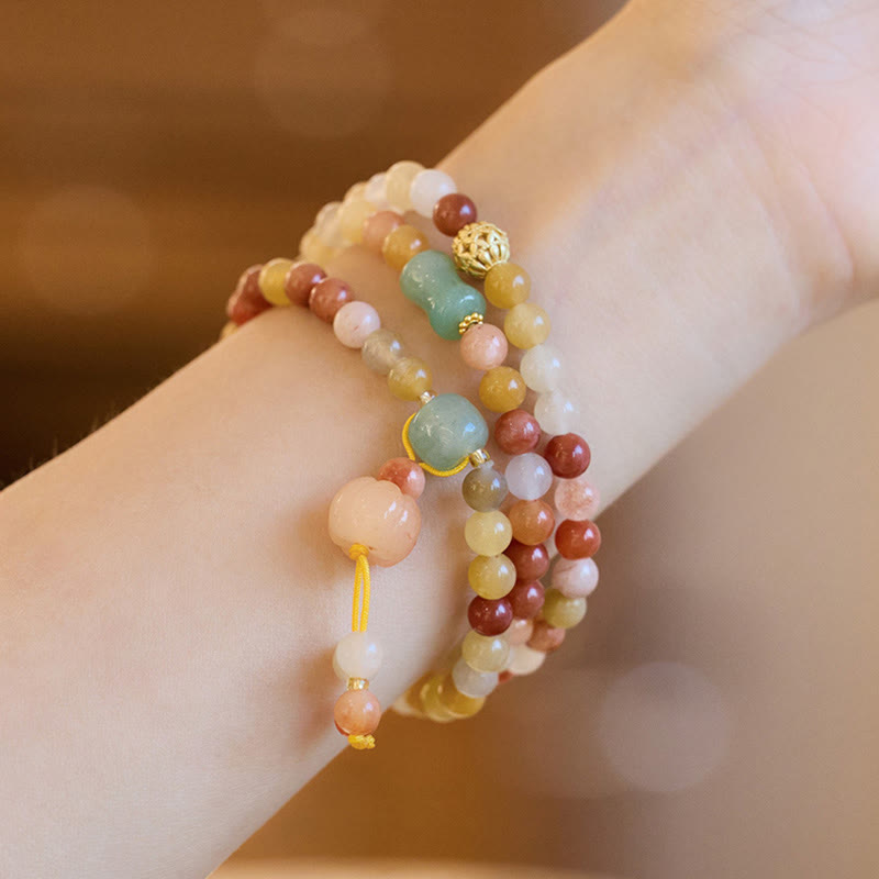 Mehrschichtiges Armband aus Jade und goldenen Perlen am Handgelenk getragen.