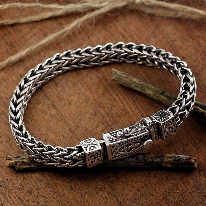 Silbernes Drachen Armband mit Flechtmuster auf Holzhintergrund elegant.