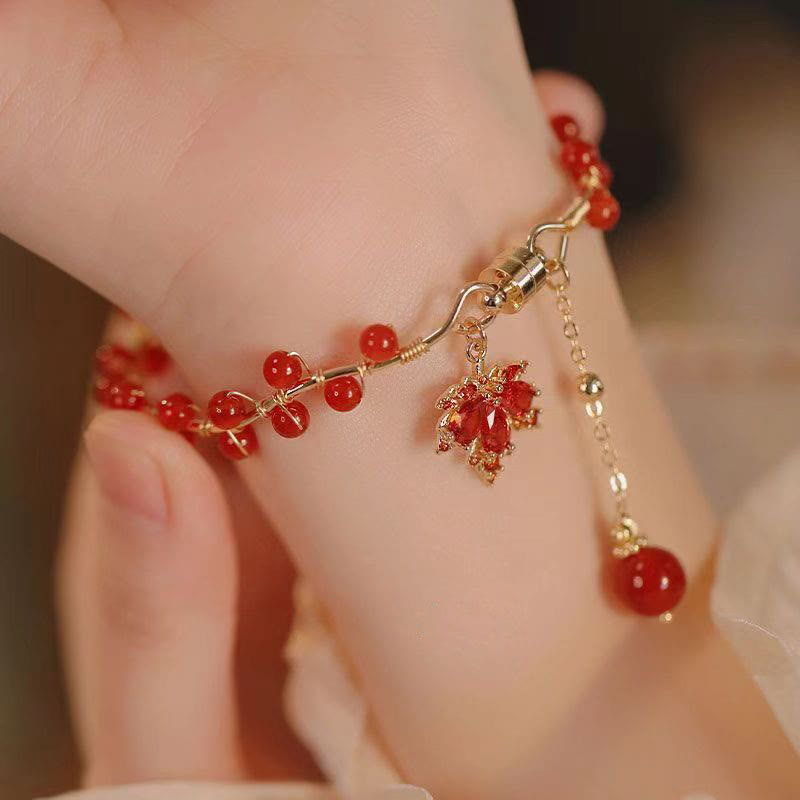 Rotes Armband mit Ahornblatt Charm und Glücksperlen am Handgelenk