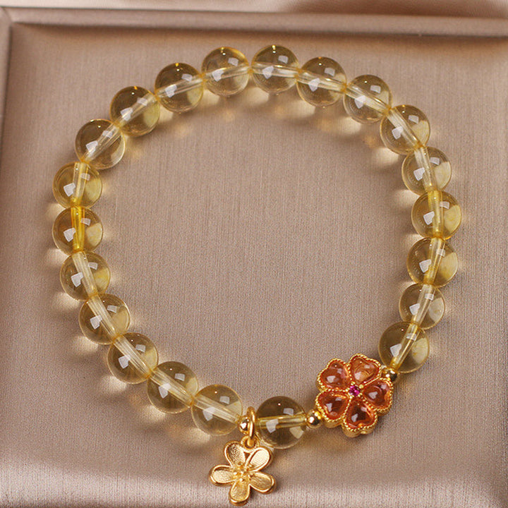 Armband Citrin mit goldenen Blütenanhängern elastisch getragen