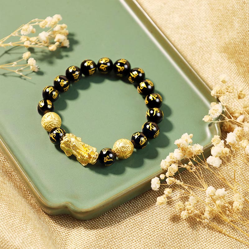 Schwarzes Obsidian Armband mit Golddetails auf grünem Tablett Flat Lay