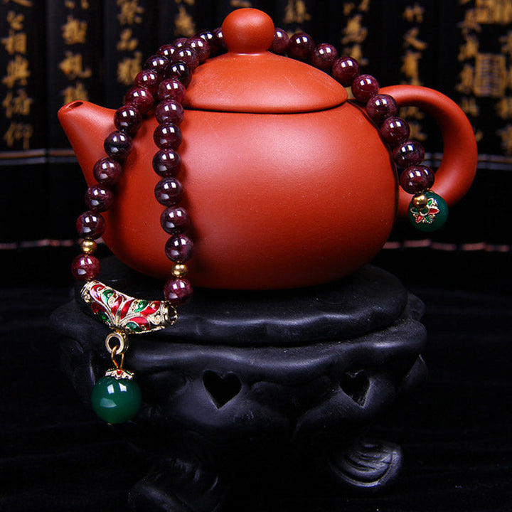 Armband Granat – Segen mit roter Teekanne und schwarzem Ständer.