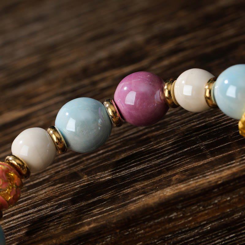 Armband – Schutz & Wohlstand & Energie: Bunte Edelstein-Perlen mit goldenen Zwischenelementen auf Holz.