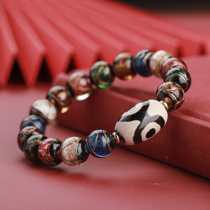 Armband – Wohlstand Balance mit bunten Perlen auf rosa Untergrund.