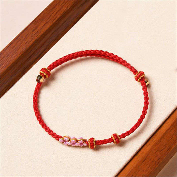 Rotes Armband Pfirsichblüte mit goldenen Perlen Schutz elegant