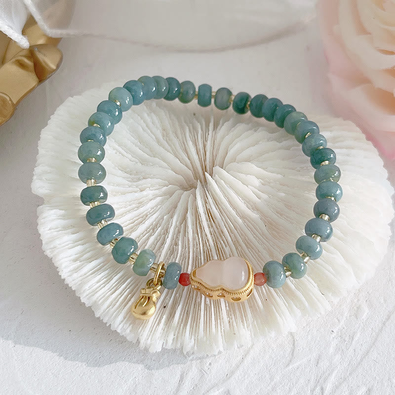 Grünes Jade Armband mit goldenen Charms auf weißer Bürste präsentiert.