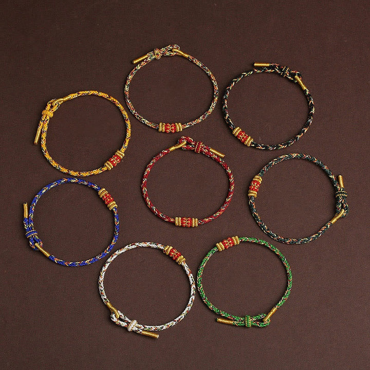 Acht bunte geflochtene Armbänder mit Knoten und goldenen Akzenten.