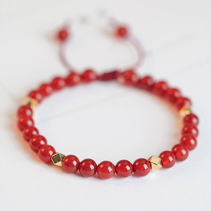 Rotes Achat Armband mit goldenen Perlen elastisch Handgelenk getragen.