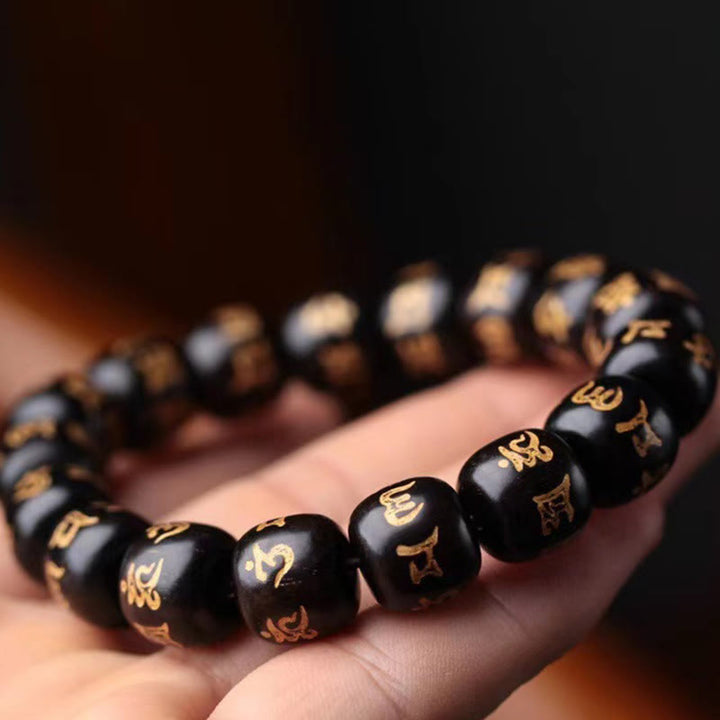 Schwarzes Ebenholz Armband mit goldenen Om Mani Padme Hum Symbolen elastisch.
