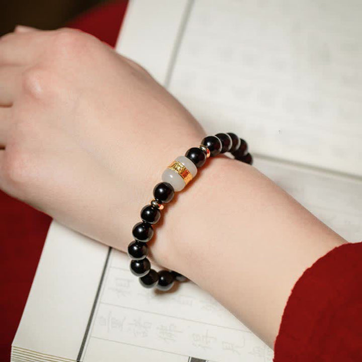 Schwarzes Obsidian Armband mit Om Mani Padme Hum Anhänger am Handgelenk