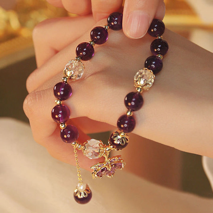 Amethyst Armband mit goldenen Perlen und Kristallanhängern elegant am Handgelenk.