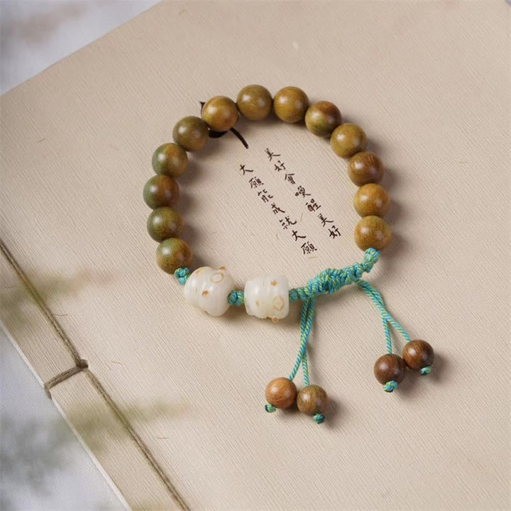 Sandelholz Bodhi Armband mit weißen Perlen und türkisem Seidenfaden getragen