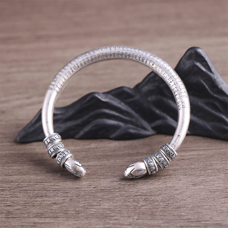 Silbernes Armband mit Om Mani Padme Hum Verzierung auf Holz Hintergrund.