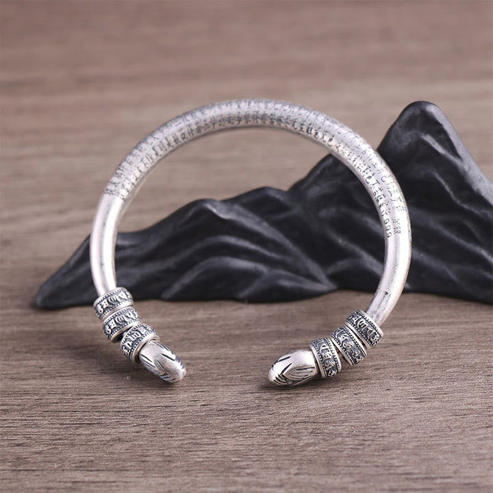 Silbernes Armband mit Om Mani Padme Hum Verzierung auf Holz Hintergrund.
