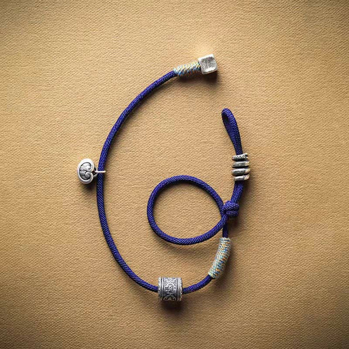 Blaues Armband Om Mani Padme Hum Doppelgeflochten auf beigem Untergrund Flat Lay