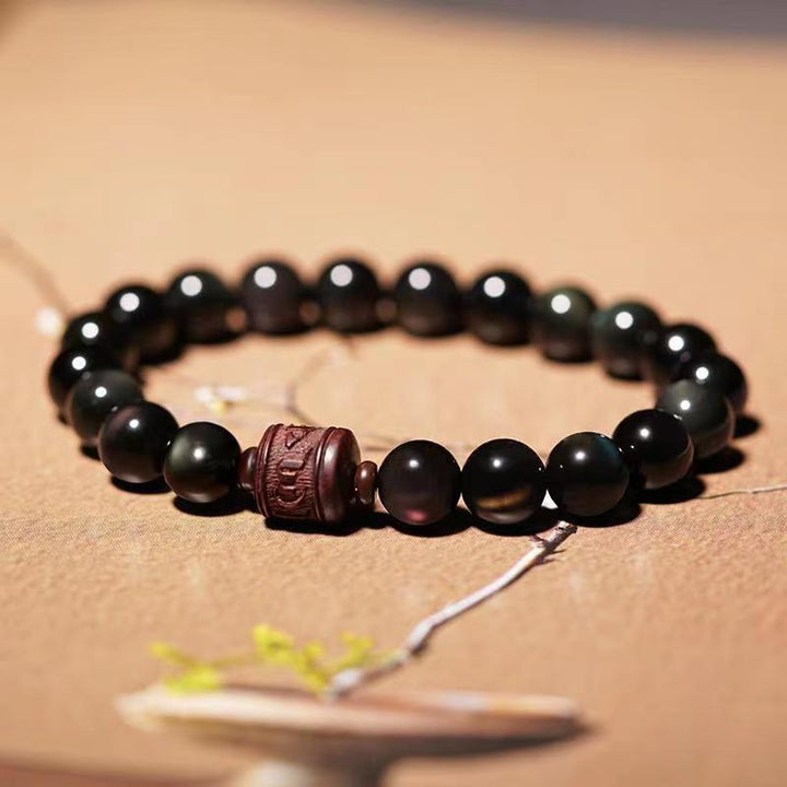 Schwarzes Obsidian Armband mit braunem Lederspacer elegant präsentiert.