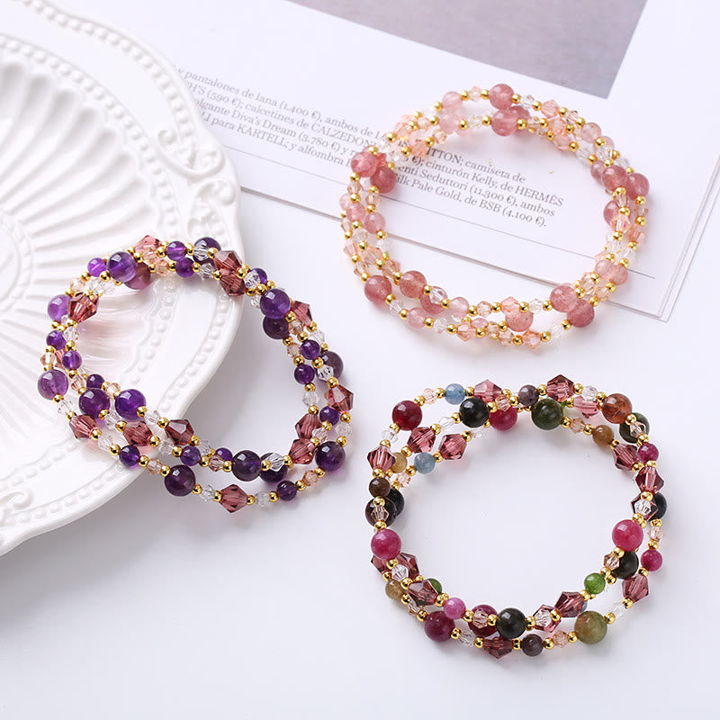 Drei bunte Armbänder mit Edelsteinen und Perlmutt flach arrangiert präsentiert.