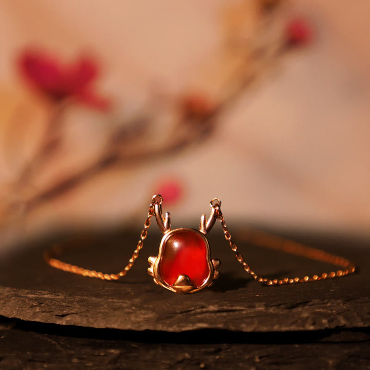 Rotes Achat Armband mit Fu-Zeichen Anhänger auf Holz Natur.