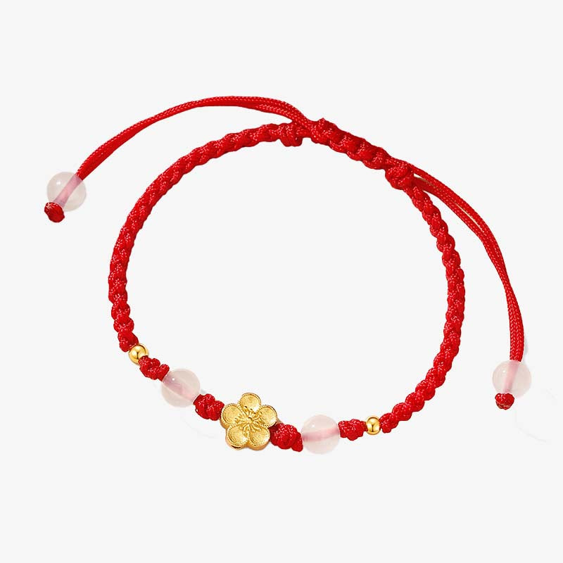 Rotes Armband mit Pfirsichblüte Charm elegant gewunden.