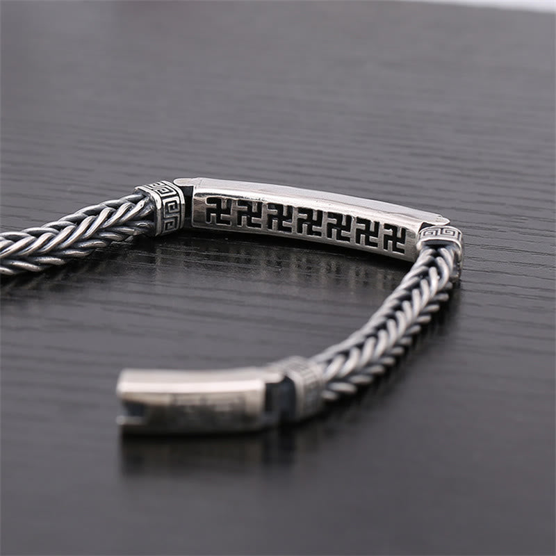 Silbernes Armband mit Swastika-Gravur auf dunklem Hintergrund elegant präsentiert.