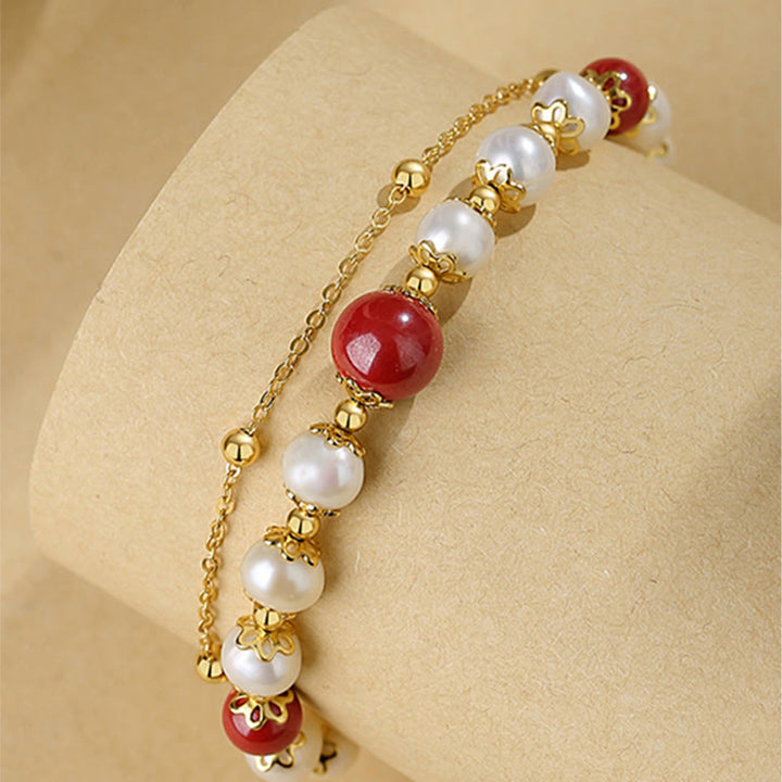 Elegantes Armband mit roten Perlen und weißen Perlen vergoldet.