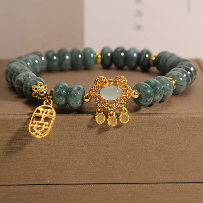 Jade Armband mit goldenen Elementen auf beigem Untergrund elegant.