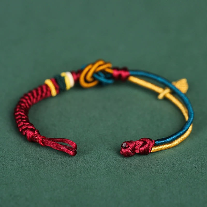 Tibetisches Armband mit bunten Knoten und Blattanhänger auf grünem Hintergrund