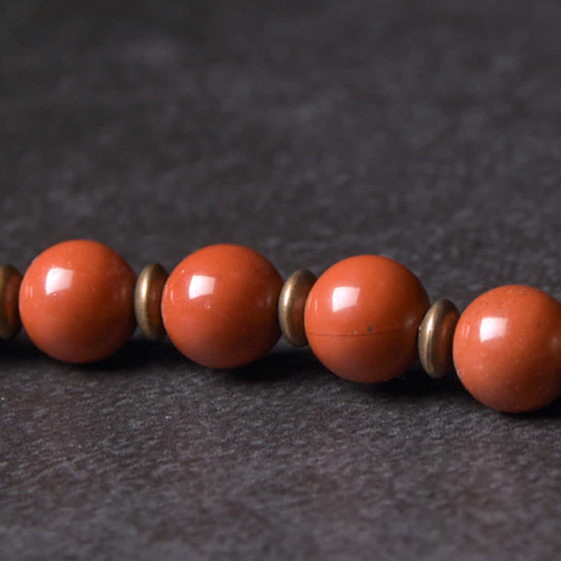 Rotes Jaspis Armband mit Metallperlen auf dunklem Untergrund Flachaufnahme