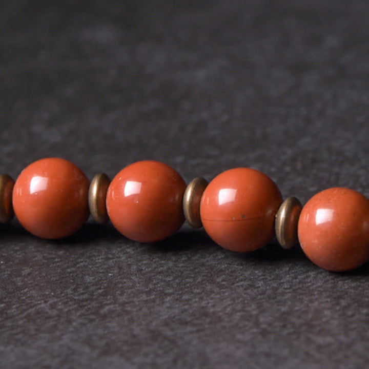Rotes Jaspis Armband mit Metallperlen auf dunklem Untergrund Flachaufnahme