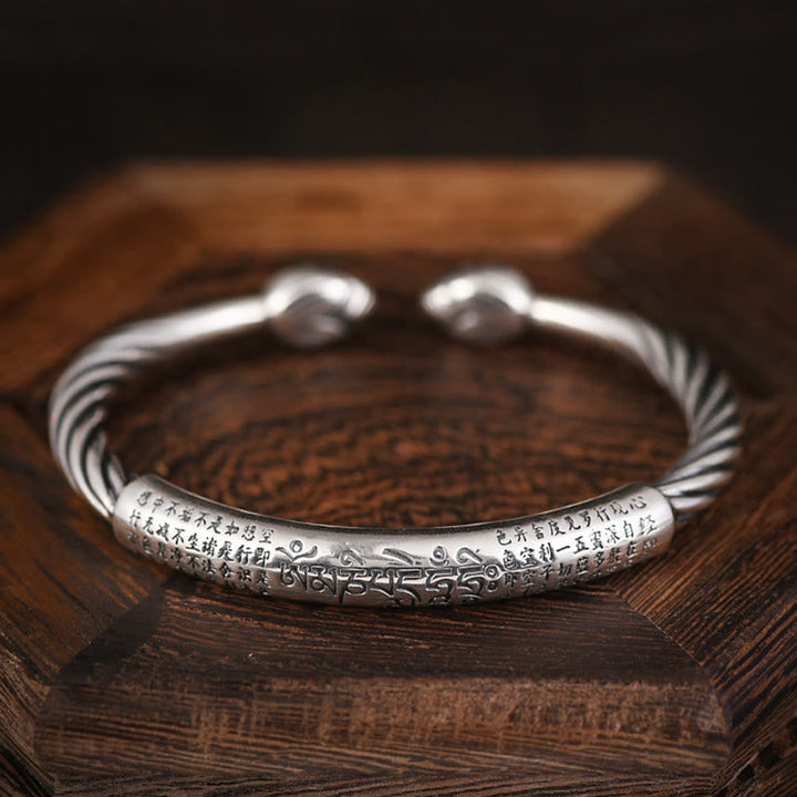 Silbernes Armband Om Mani Padme Hum Herzsutra auf Holzoberfläche, gedrehtes Design