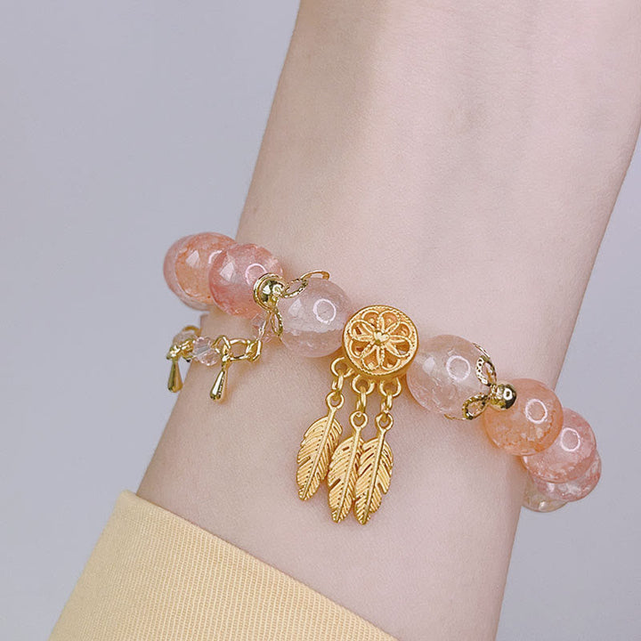 Roségold Armband mit Perlen und Federn Anhängern am Handgelenk getragen