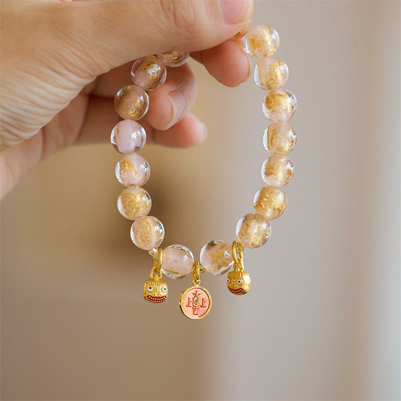 Armband mit goldenem Glücksbringer Anhänger am Handgelenk getragen
