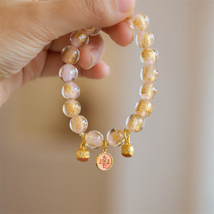 Armband mit goldenem Glücksbringer Anhänger am Handgelenk getragen