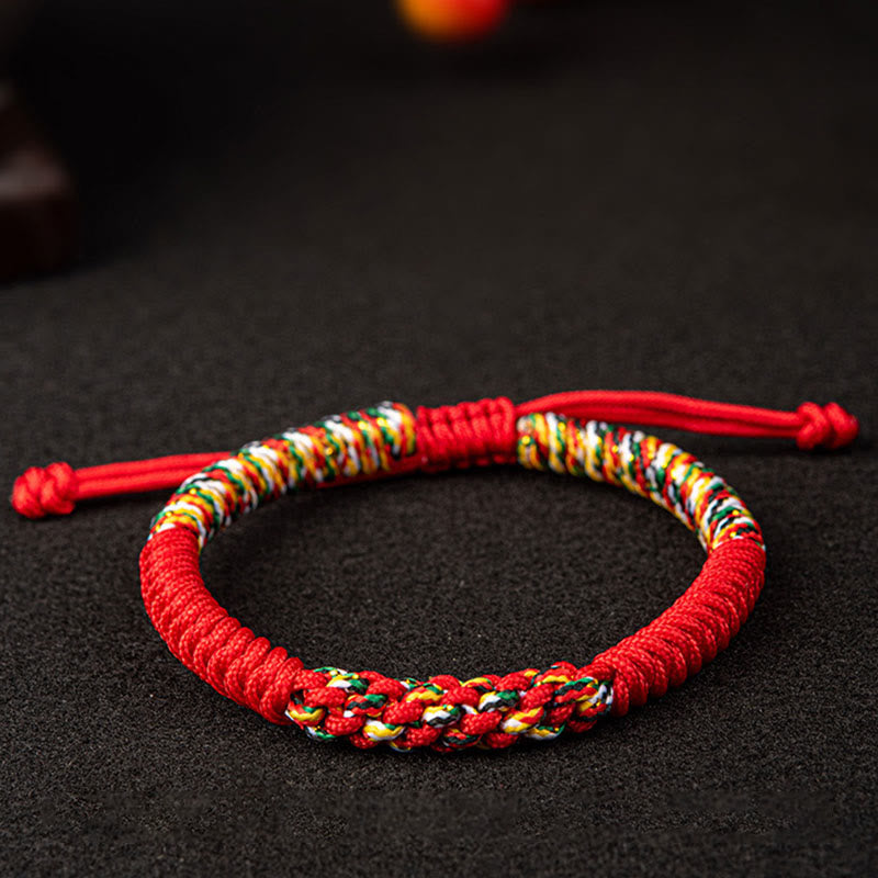 Rotes Mala-Armband mit bunten Wicklungen auf dunklem Hintergrund flach.