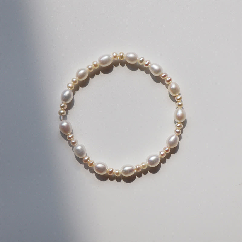 Elegantes Perlenarmband mit weißen und goldfarbenen Perlen, elastisch gefädelt.