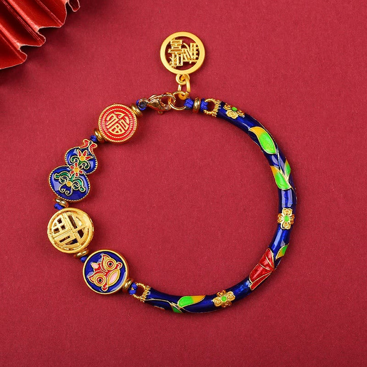 Armband – Glück & Wohlstand Energie mit goldenen Charms auf rotem Hintergrund