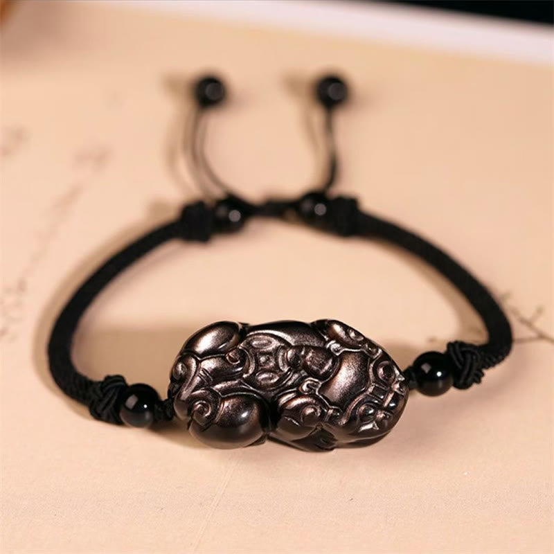 Schwarzes Armband mit Pixiu Anhänger auf beiger Oberfläche eleganter Schmuck
