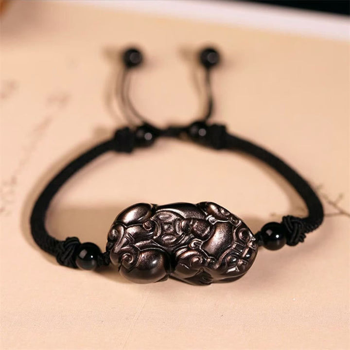 Schwarzes Armband mit Pixiu Anhänger auf beiger Oberfläche eleganter Schmuck