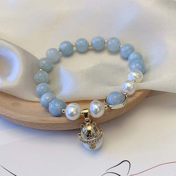 Armband Aquamarin Perle Katze Glück Heilung Holzschale Nahaufnahme blau weiß