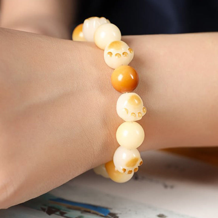 Armband Sandelholz Bodhi Katze am Handgelenk mit beige Perlen getragen.