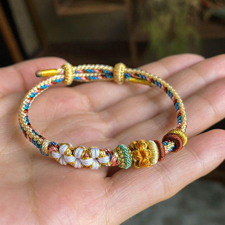 Armband Pfirsichblüte mit goldenen Perlen und farbigen Fäden elastisch.