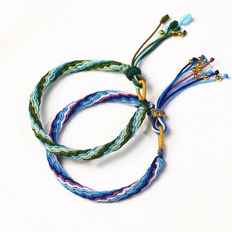 Zwei bunte Armbänder mit Perlen und Quasten auf weißem Hintergrund Flatlays