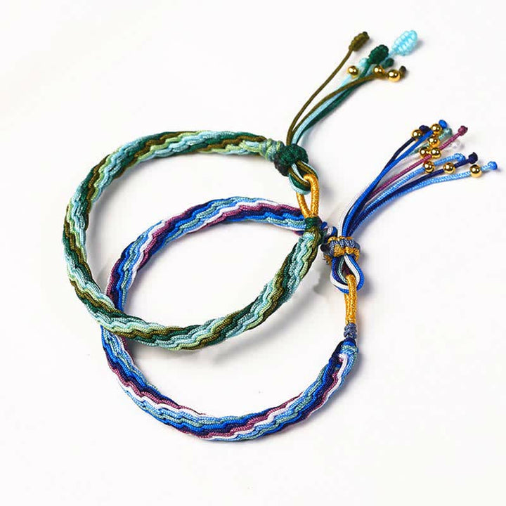 Zwei bunte Armbänder mit Perlen und Quasten auf weißem Hintergrund Flatlays