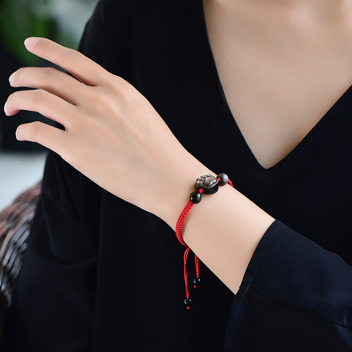 Rotes Armband mit schwarzem Obsidian Katze Anhänger am Handgelenk getragen